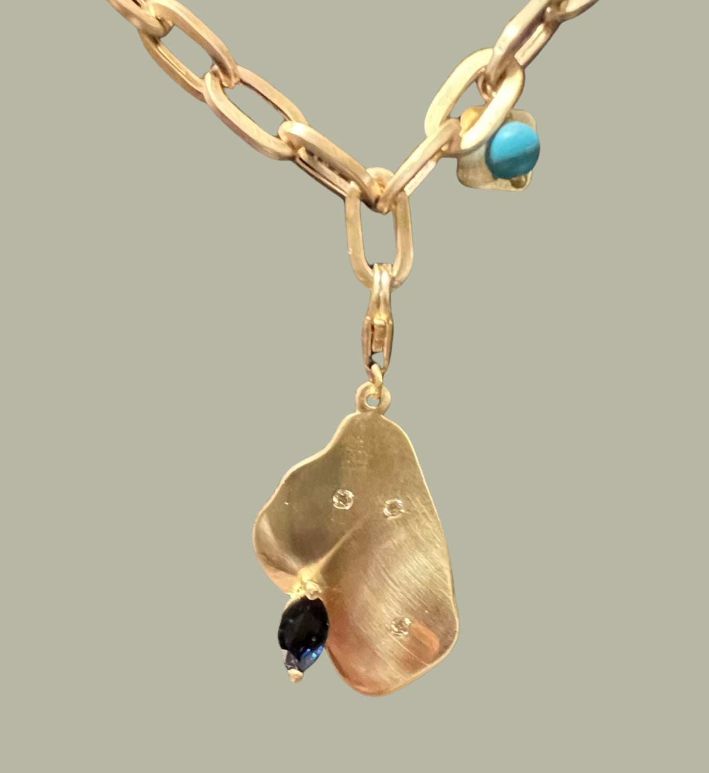 Organic shaped charm with blue sapphire and diamonds in yellow gold